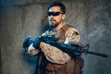 American private military contractor holding rifle. Image on a dark background