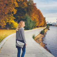 Woman walking in autumn park near river