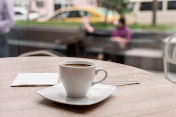 Cup of coffee in a cafe, bar on the background of city life behind glass