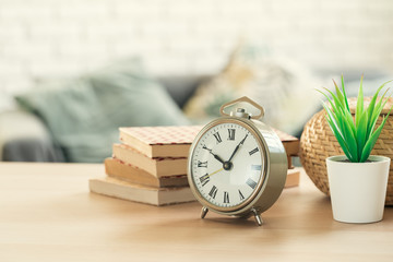 Old-fashioned alarm clock and house plant on wooden table