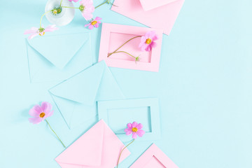 Flowers composition romantic. Pink cosmos flowers, pink and blue envelopes on pastel blue background. Flat lay, top view, copy space