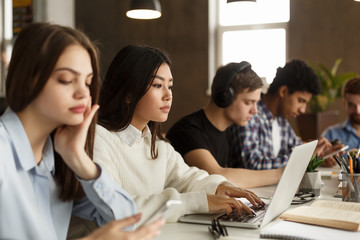 Diverse students sitting at college library, doing homework