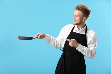 Handsome male chef with frying pan on color background