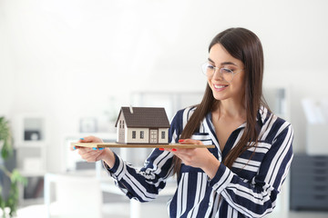 Beautiful female architect with model of house in office