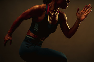 Close up of lean healthy core muscle of athletic asian woman sprint running to the finish line with warm light from the right, concept for healthy lifestyle and sport.