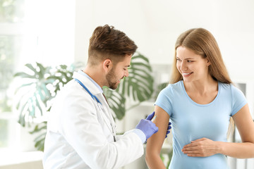 Doctor vaccinating pregnant woman in clinic