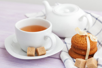 Fototapeta na wymiar Cup of tea with cookies over lilac wooden background
