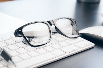 Glasses on laptop with pen, close up