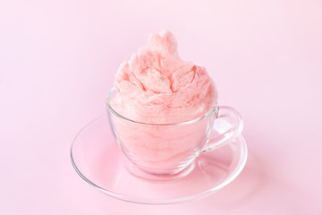 Glass cup with tasty cotton candy on color background