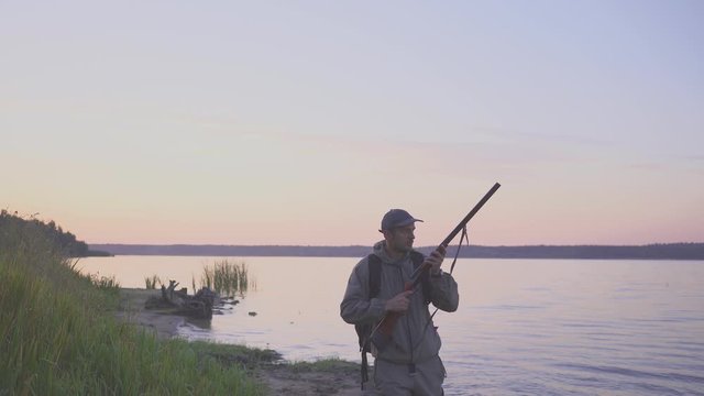 Silhouette of the hunter on a duck hunt near a beautiful lake. Shooting hunter.