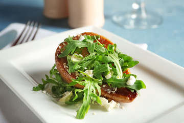 Tasty pear with fresh arugula on plate, closeup