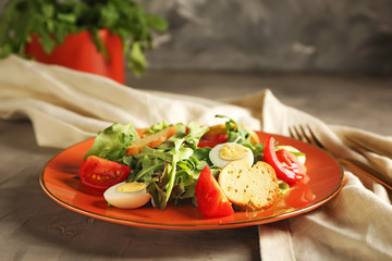Plate with tasty arugula salad on table