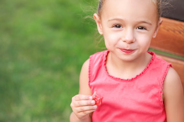 Cute little girl eating sweet watermelon in park