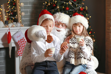 Fototapeta na wymiar Santa Claus and little children with milk and cookies in room decorated for Christmas