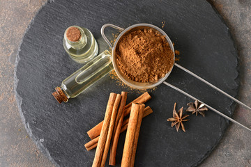 Aromatic cinnamon sticks, essential oil and powder on table