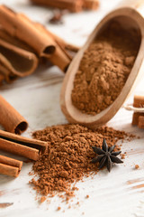 Cinnamon powder and sticks on light wooden background
