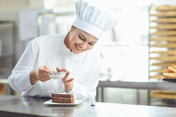 Confectioner decorating chocolate cake in pastry shop. - obrazy, fototapety, plakaty