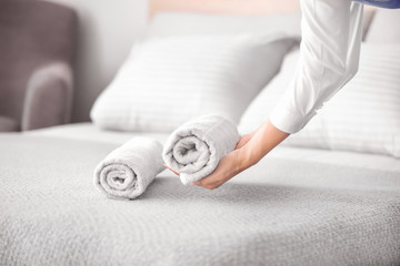 Female housekeeper putting clean towel on bed