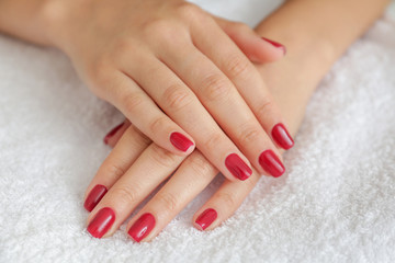 Manicured hands of young woman on towel, closeup