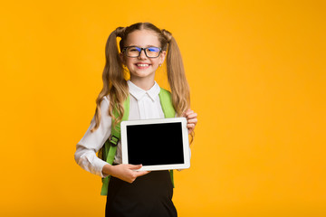 Elementary Student Girl Showing Blank Tablet Screen, Yellow Studio Background