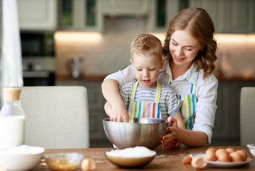 happy family in kitchen. mother and child preparing dough, bake cookies.