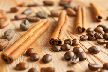 Aromatic cinnamon with coffee beans on wooden table, closeup