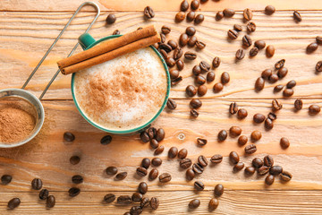 Cup of coffee with cinnamon and beans on wooden table