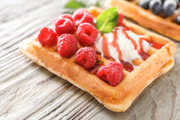 Sweet waffle with ice cream and raspberry on wooden table