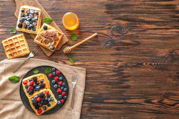 Sweet waffles with berries and honey on wooden table