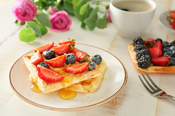 Plate with tasty sweet waffles and berries on table