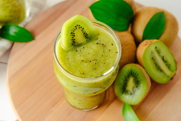 Glass of tasty kiwi smoothie on wooden board, closeup