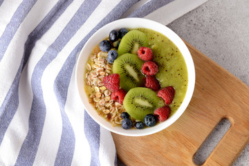 Bowl with tasty oat flakes and fruits on table