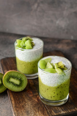 Glasses with tasty kiwi dessert on wooden board