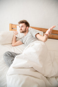 Young angry caucasian man in bed , trying to sleep after being awakened in the morning from the bed. Lifestyle at home concept