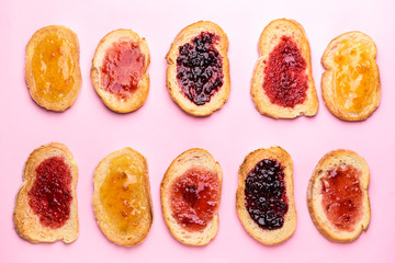 Tasty toasted bread with different jams on color background