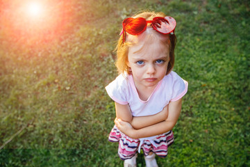 Unhappy beautiful little girl in a red dress with a toy bear