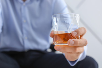 Man with glass of whiskey at home, closeup