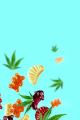 Colored gummies fly along with cannabis leaves. Chewing candies with CBD oil, THC. Creative background, minimalism.