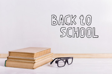 Books and glasses on the table against the background of a white board. Copy space.