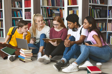 Group of diverse students sitting on floor at library