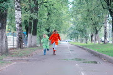 children run in raincoats / summer park, rain, walk brother and sister, children boy and girl