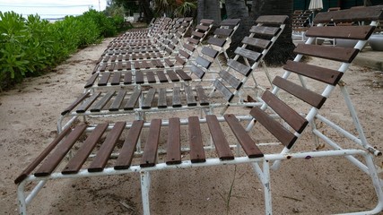 A row of wooden beach chairs by the sea