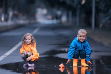 brother and sister play boats in a puddle / raincoats clothes, autumn weather children play paper boats