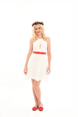 full length portrait of blonde girl wearing a white dress and flower crown.  Standing pose, isolated against a  white studio background.