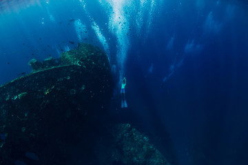 Freediver man dive underwater at shipwreck. Freediving in ocean