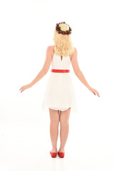 full length portrait of blonde girl wearing a white dress and flower crown.  Standing pose, isolated against a  white studio background.