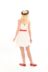full length portrait of blonde girl wearing a white dress and flower crown.  Standing pose, isolated against a  white studio background.
