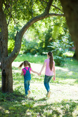 Fototapeta premium Two girls, big and small, are walking through the forest.