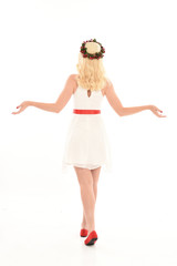 full length portrait of blonde girl wearing a white dress and flower crown.  Standing pose, isolated against a  white studio background.