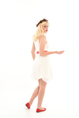 full length portrait of blonde girl wearing a white dress and flower crown.  Standing pose, isolated against a  white studio background.